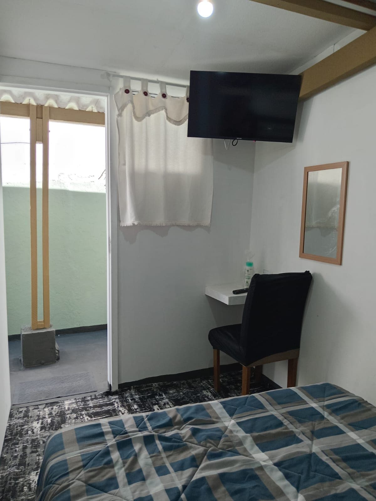 Suíte com TV de tela plana, bancada de trabalho e porta para a varanda